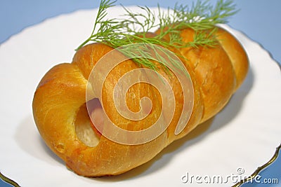 Bun with sausage on a plate on a gray background. Stock Photo