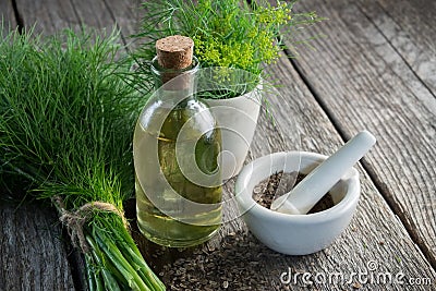 Bunch of aromatic fresh green dill, mortar of fennel seeds and dill oil bottle. Stock Photo