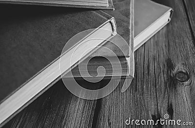 A bunch of books with a scarlet cover on a wooden table. books with a red cover lie on a wooden table. Black and white Stock Photo