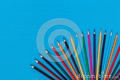 A bunch of crayons arranged in a semi circle on a ocean blue background, shot from above, aligned at the bottom, closeup Stock Photo
