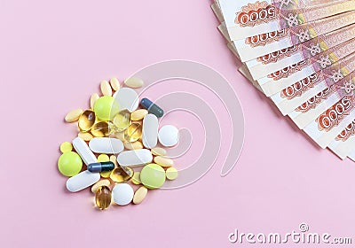 A bunch of colorful pills and Russian bills on a pink background. The cost of treatment and health concept Stock Photo