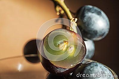 A bunch of dark blue grapes on a dark background in the conditions of artificial hard lighting close up. Grapes, cut in half, grap Stock Photo