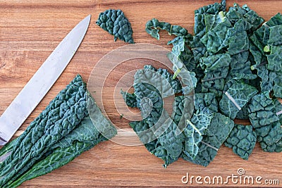 Bunch of dark green, crinkly, sliced Lacinato Kale leaves, on a wood cutting board, chefs knife Stock Photo