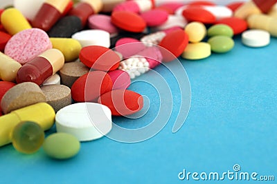 A bunch of different bright pills and capsules lie on a blue background. Stock Photo