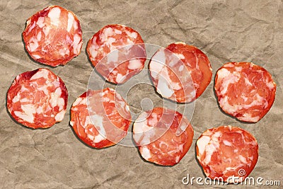 Bunch Of Eight Pork Salami Slices Set On Crumpled Striped Manila Brown Kraft Paper Stock Photo