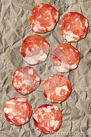 Bunch Of Eight Pork Salami Slices Set On Crumpled Striped Manila Brown Kraft Paper Stock Photo