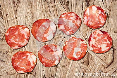 Bunch of Eight Pork Salami Slices Set On Rustic Wooden Chipboard Rough Grunge Surface Stock Photo