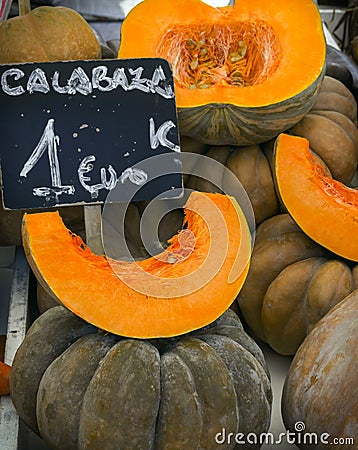Bunch of Fairytale pumpkins whole cut in wedges and halved at farmers market with chalkboard price tags in Spanish. Thanksgiving Stock Photo