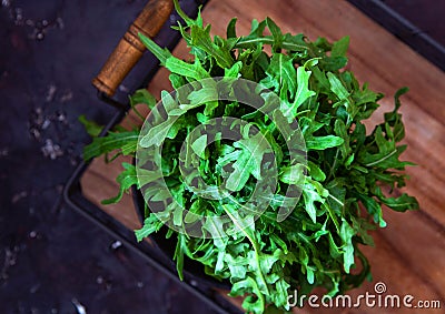 Bunch of fresh arugula leaves on a wooden tray. Top view Stock Photo
