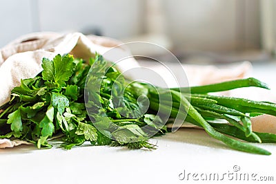 Bunch of fresh parsley, dill and spring onion in canvas reusable shopping tote bag on kitchen table Stock Photo
