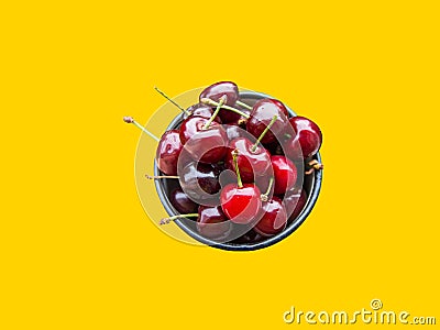 Bunch of freshly picked red glossy sweet cherries in mug on bright yellow background. Summer berries fruits Stock Photo