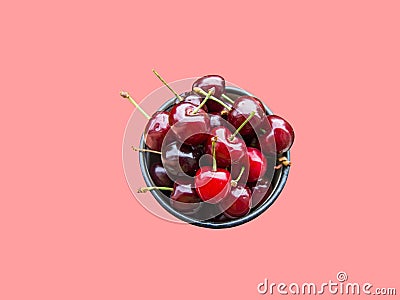 Bunch of freshly picked red glossy sweet cherries in mug on pink background. Summer berries fruits healthy plant based diet Stock Photo