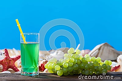 Bunch of grapes. Grape juice in a glass on the shore of the sea beach on a sunny day. Sunny rest during the holidays Stock Photo