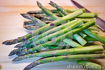 Bunch of green fresh asparagus or spargel in german on the choping plate with kitchen knife Stock Photo