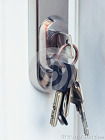 Bunch of keys inserted in door lock on white door Stock Photo