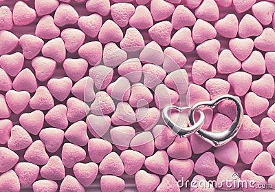 Bunch of little pink candy scattered, silver pendant two hearts Stock Photo