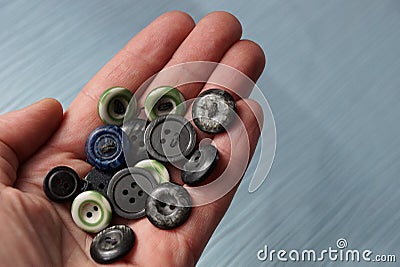 A bunch of old colored buttons on an open palm above the table Stock Photo