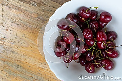 Bunch of red cherries mature tasty in a white ceramic bowl on a wooden table autumn harvest Stock Photo