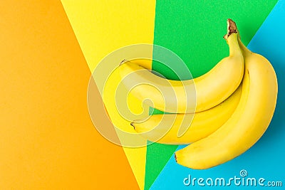 Bunch of ripe bananas on rainbow multicolored pinwheel striped background. Creative trendy flat lay. Healthy food clean eating Stock Photo