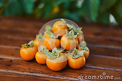 Bunch of ripe orange persimmons lies on a brown wooden table Stock Photo