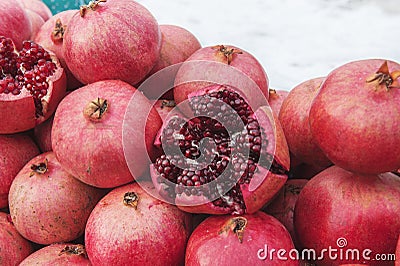 A bunch of ripe red pomegranates on the street in winter. One of the fruits is cut in half. Visible grains and bones Stock Photo