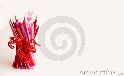 A bunch of sharpened pencils, felt-tip pens in red and pink, and a pen in the shape of a bunny Stock Photo