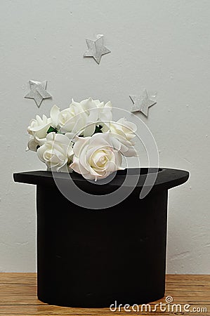 A bunch of white roses in a magicians hat with silver stars Stock Photo