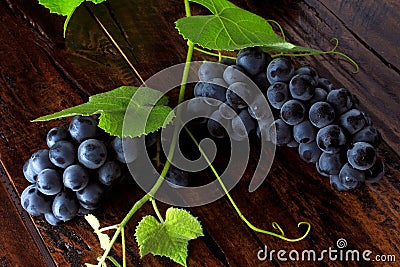 Bunches of fresh grapes with branches and leaves on rustic wooden table Stock Photo