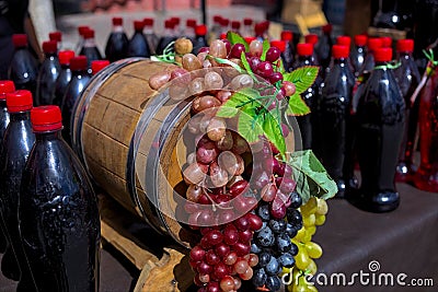 Bunches of white, pink and dark grapes on an old wooden wine barrel. Editorial Stock Photo