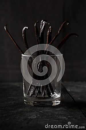 Bundle of dried bourbon vanilla beans or pods in glass on black wood background Stock Photo