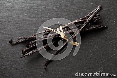 Bundle of tied, dried bourbon vanilla beans or pods on black stone board flat lay top view Stock Photo