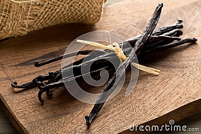 Bundle of tied, dried bourbon vanilla beans or pods on brown wooden cutting board Stock Photo