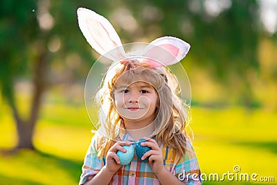 Bunny child boy face. Child boy hunting easter eggs. Child boy with easter eggs and bunny ears in park. Stock Photo
