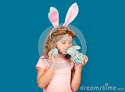 Bunny child. Child boy hunting easter eggs. Child boy with easter eggs and bunny ears isolated on blue background. Funny Stock Photo