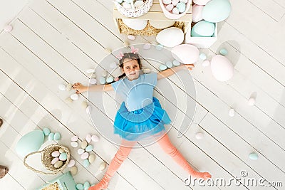 Getting ready to Easter. Lovely little girl holding an Easter egg and smiling with decoration in the background Stock Photo