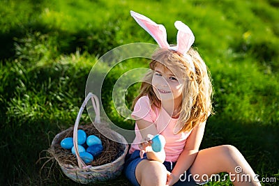 Bunny easter child. Kids hunting easter eggs. Boy with easter eggs and bunny ears in backyard. Easter holiday. Stock Photo