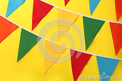 Bunting with colorful triangular flags on yellow background. Festive decor Stock Photo