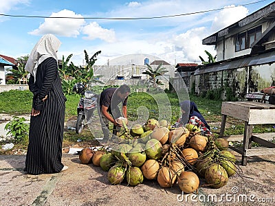 Buntok, Indonesia. March 27, 2023. The coconut seller is peeling coconuts ordered by a buyer. Editorial Stock Photo