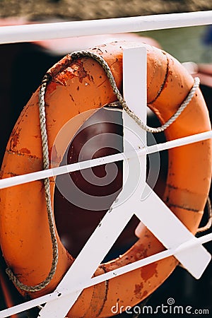 Buoy or lifebuoy ring on shipboard in evening sea. Flotation device on ship side on seascape. Safety, rescue, life Stock Photo