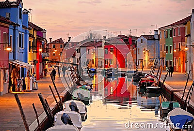 Burano island picturesque street with small colored houses, tourists on street and beautiful water reflections on cana Editorial Stock Photo