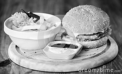 Burger with cheese meat and salad. Cheat meal. Delicious burger with sesame seeds. Burger menu. High calorie snack Stock Photo