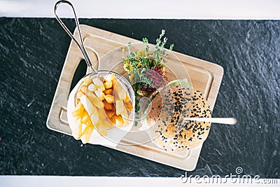 Burger with fries and vegetables on a board. Dinner main dish on a wooden table. Traditional polish cuisine Stock Photo