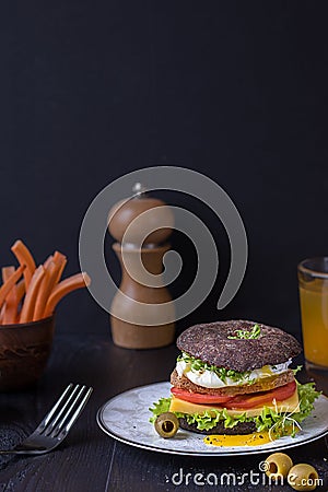 Burger with tomato, cheese, Benedict egg and Fresh Greens on a plate on a dark background and Stock Photo