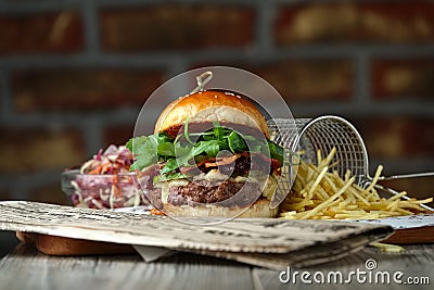 Burger on the wooden table with cheese, bacon, tomatos, green and red salad and french fries Stock Photo