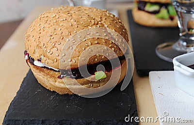 Burgers closeup. Beer, berry sauce on a slate boards. Wooden textural background Stock Photo