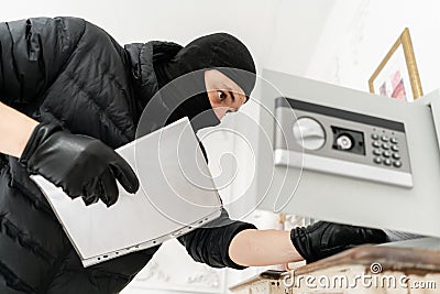 The thief opens the electronic safe. The burglar commits a crime in Luxury apartment with stucco. Thief with black Stock Photo