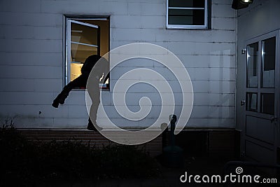 Burglar Entering In A House Through A Window Stock Photo