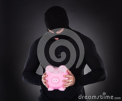 Burglar stealing a pink piggy bank Stock Photo