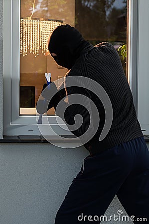 Burglar trying to open a window Stock Photo