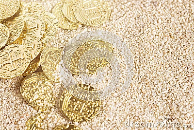 Buried Pirate Treasure Gold Coins in the Sand on a Sandy Beach Stock Photo